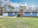 Charming single-story home with blue siding, brick chimney, and well-maintained front lawn at 3322 Heather Glynn Dr, Mulberry, FL 33860