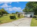 Inviting home featuring a long driveway and a detached garage, surrounded by lush greenery at 14285 Oconner Rd, Kathleen, FL 33849