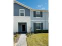 Inviting two-story townhome featuring a mix of siding, manicured lawn, and walkway leading to the front door at 627 Jasmine Ln, Davenport, FL 33897