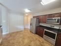 Well-lit kitchen featuring stainless steel appliances, dark wood cabinets, and stylish tile flooring at 6187 Brookhill Cir, Orlando, FL 32810