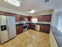 Bright kitchen featuring stainless steel appliances, dark wood cabinets, and granite countertops at 6187 Brookhill Cir, Orlando, FL 32810