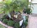 Close up of an ornate garden with lush foliage and decorative heron sculptures lining the brick driveway at 2188 Palm Tree Dr, Kissimmee, FL 34759