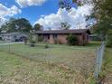 View of single-story brick home with a chain link fence and landscaped yard at 2865 Barton Pl, Bartow, FL 33830