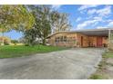 Inviting single-story home with a large driveway, mature trees, and a covered carport at 520 S Orange Ave, Fort Meade, FL 33841