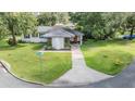 Inviting single-story home with an orange front door, lush green lawn, and mature trees at 407 W Oak Dr, Lakeland, FL 33803