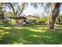 Charming home featuring a well-maintained lawn and an inviting, shaded outdoor seating area at 9415 Cat Track Trl, Lake Wales, FL 33898