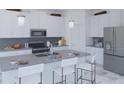 Bright kitchen featuring white cabinets, stainless steel appliances, an island with seating, and modern pendant lighting at 5103 Bridgehaven Rd, Davenport, FL 33837