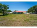Inviting single-story home with a red roof, lush front yard, and a glimpse of the lake in the background at 5020 Old Lucerne Park Rd, Winter Haven, FL 33881