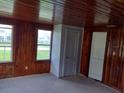 Cozy living room features wood-paneled walls, light carpet, and bright windows looking out to the lawn at 102 Se 6Th Ave, Mulberry, FL 33860
