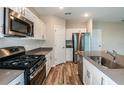 Modern kitchen with white cabinets, stainless steel appliances, an island with seating, and wood-look floors at 1014 Foreshore Ln, Haines City, FL 33844