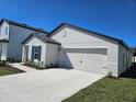 A newly built single-Gathering home featuring an attached two-car garage, concrete driveway and manicured landscaping at 1649 Nantucket Way, Winter Haven, FL 33884