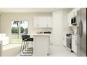 Bright, all-white kitchen with stainless steel appliances, island seating, and a sliding glass door to the patio at 2066 Lasso Loop, Eagle Lake, FL 33839