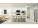 Bright, all-white kitchen featuring a center island with bar seating, stainless steel appliances, and adjacent dining area at 2070 Lasso Loop, Eagle Lake, FL 33839