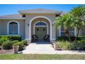 Inviting front entrance with arched doorway, olive-green door, seating and potted plants at 119 Lake Mariam Way, Winter Haven, FL 33884