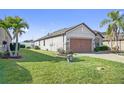 Spacious home featuring manicured lawn, palm trees, and a two-car garage with brick accents at 474 Del Sol Ave, Davenport, FL 33837