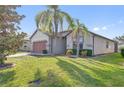 Inviting home exterior with lush green lawn, mature palm trees, and a brick-accented two-car garage at 474 Del Sol Ave, Davenport, FL 33837