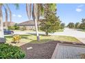 Well-maintained front yard with lush landscaping, palm trees, and paver walkway leading to the home at 474 Del Sol Ave, Davenport, FL 33837