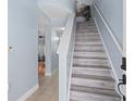 Bright entryway featuring light wood stairs, soft blue walls, and a hallway leading to the kitchen and living areas at 7636 Heritage Crossing Way, Reunion, FL 34747