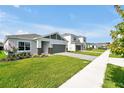 Street view of modern single-Gathering homes with gray brick accents, well-manicured lawns, and paved driveways at 5774 Greenery Ln, St Cloud, FL 34771