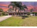 Charming single-story home with a well-manicured lawn, palm trees, and a cozy front porch with rocking chairs at 1062 Mayflower Ave, Deltona, FL 32725