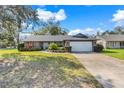 Single-story home features brick accents, mature trees and an attached two car garage at 282 Lake Griffin Cir, Casselberry, FL 32707