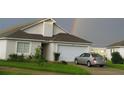 Suburban home with an attached garage, driveway, and green lawn under a vibrant rainbow sky at 602 Hillcrest Dr, Davenport, FL 33897