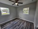 Cozy bedroom with wood-look floors, a ceiling fan, and plenty of natural light from two windows at 1011 Old Lake Alfred Rd, Auburndale, FL 33823