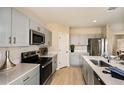 Bright kitchen with gray cabinets, stainless steel appliances, quartz countertops, and modern fixtures at 1780 Frogmore Ave, Haines City, FL 33844