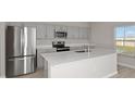 Modern kitchen with stainless steel appliances, gray cabinets, and a large quartz island at 1018 Foreshore Ln, Haines City, FL 33844