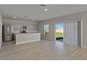 Open concept living area featuring wood-look floors and sliding glass doors to the backyard at 1018 Foreshore Ln, Haines City, FL 33844