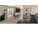 Open concept living room featuring wood floors and a large tv at 112 Thorne Meadow Pass, Davenport, FL 33897