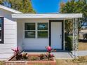 Inviting front entrance with a white door, black trim, and a small garden bed with colorful plants at 218 W Magnolia St, Clermont, FL 34711