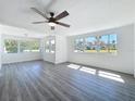 Bright living room with large windows, modern ceiling fan, and stylish gray laminate flooring at 218 W Magnolia St, Clermont, FL 34711