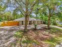Aerial side view of a well-maintained home with a wooden fence, mature trees, and a spacious lot at 31632 Spruce Dr, Eustis, FL 32736