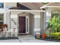 Close-up of the home's entrance featuring a stylish door, stone accents, and lush landscaping at 638 Coral Way, Winter Springs, FL 32708