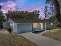 Charming blue brick home with a concrete driveway and mature landscaping at dusk at 501 15Th Ne Ct, Winter Haven, FL 33881