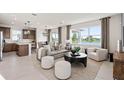 Bright, open living room featuring stylish furnishings, modern lighting, and a large window with a serene lake view at 1423 Hamilton Way, Lake Alfred, FL 33850