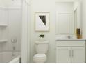 Well-lit bathroom with a shower, bathtub, toilet, and white vanity, complemented by modern artwork at 1177 Hour Glass Rd, Lakeland, FL 33801