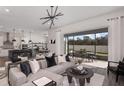Open-concept living room with gray sofa, pendant lighting, kitchen access and sliding glass doors to an outdoor patio at 1687 Ruby Ln, Lake Alfred, FL 33850