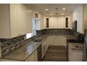 Modern kitchen with white cabinets, granite countertops, stainless steel appliances, and mosaic tile backsplash at 3821 Whitedove Dr, Lakeland, FL 33812