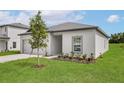A view of the home's side exterior, showing the landscaping, lawn, window, and a partial view of the garage at 13276 Tula Loop, Astatula, FL 34705