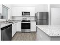 Modern kitchen featuring stainless steel appliances, granite countertops, and bright white cabinetry at 13276 Tula Loop, Astatula, FL 34705
