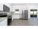 Well-lit kitchen with stainless steel appliances, white cabinets, and a view of the backyard at 13438 Leaping Water Way, Astatula, FL 34705