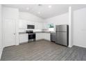 Modern kitchen with stainless steel appliances, white cabinetry, and beautiful wood-look flooring at 13438 Leaping Water Way, Astatula, FL 34705