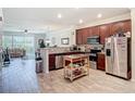 Open kitchen featuring stainless steel appliances, granite countertops, dark wood cabinets, and wood-look floors at 3926 Grassland Dr, Orlando, FL 32824