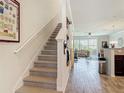 Open-concept space with a staircase, wood-look floors, and a view into the living room with a sliding glass door at 3926 Grassland Dr, Orlando, FL 32824