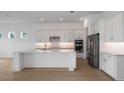 Bright, white kitchen features a large island, stainless steel appliances, and modern backsplash at 8734 Sw 55Th Street Rd, Ocala, FL 34481