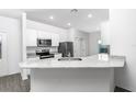 Well-lit kitchen with granite countertops, stainless steel appliances, and stylish gray flooring at 13442 Leaping Water Way, Astatula, FL 34705
