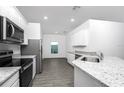 Modern kitchen featuring granite countertops, stainless steel appliances, and sleek gray flooring at 13442 Leaping Water Way, Astatula, FL 34705