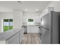 Open kitchen area with stainless steel appliances, white cabinets and a granite island at 13458 Leaping Water Way, Astatula, FL 34705